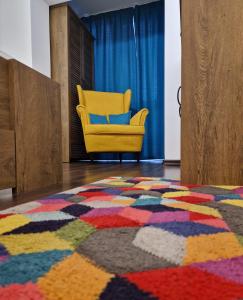 Habitación con alfombra colorida y silla amarilla en House of colors, en Petroşani