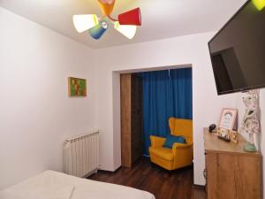 1 dormitorio con ventilador de techo y silla amarilla en House of colors, en Petroşani