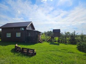 une petite maison dans un champ herbeux à côté d'une grange dans l'établissement Sajzy Ostoja - domek nad jeziorem, à Sajzy