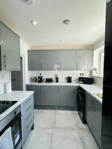 eine Küche mit weißen Schränken und einem schwarzen Gerät in der Unterkunft Deluxe Bungalow in Longham
