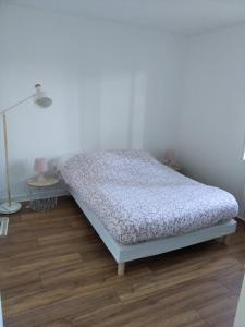 ein Schlafzimmer mit einem Bett und einer Lampe auf einem Holzboden in der Unterkunft Le Cottage in Donnery