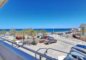 ein Parkplatz mit geparkten Autos und der Strand in der Unterkunft Maria's urban seaview apartments in Iraklio