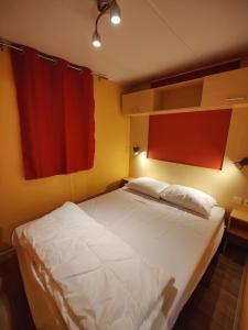 1 dormitorio con cama blanca y cortinas rojas en Camping La Saline d'Arc et Senans, en Arc-et-Senans