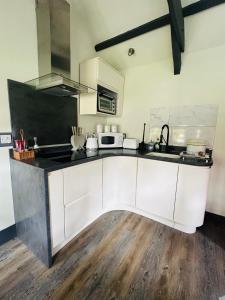 a kitchen with white cabinets and a black counter top at Tiny Romantic Retreat with Hot Tub on a Country Estate near Cardigan Bay in Eryri Snowdonia in Llanbedr +7 photos