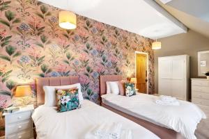 two beds in a room with floral wallpaper at The Olive Suite - 3 bedroom - Free Parking in Harrogate