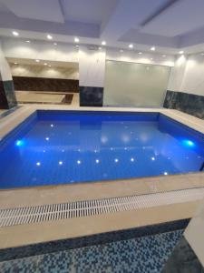 a large swimming pool with blue water in a building at اللؤلؤة الذهبي للشقق المخدومة in Medina