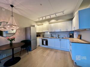 a kitchen with white cabinets and a table in it at Beachfront apartment Sørenga Oslo in Oslo