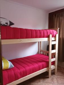 a bunk bed with a red cushion on the bottom bunk at casa a una cuadra del centrode ushuaia in Ushuaia