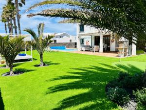 een tuin met palmbomen en een huis bij Villa Sunset Zafiro in Playa Blanca