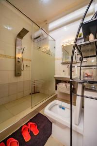 a bathroom with a shower and a toilet with red slippers at PNG Guest house Kitende in Kampala