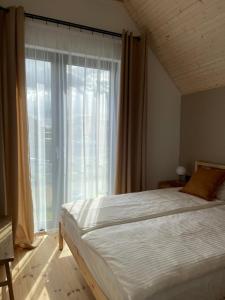 sypialnia z łóżkiem i dużym oknem w obiekcie Nadmorska Otulina - Nowoczesne dwupoziomowe domki nad morzem z dużym ogrodem w Ustce