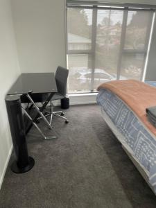 a bedroom with a desk and a bed and a window at 11 A Addison street home stay - room 2 in Auckland