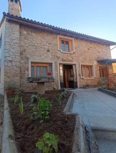 a stone house with a garden in front of it at Aires Del Ambroz in Casas del Monte
