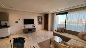 uma sala de estar com um sofá e uma televisão de ecrã plano em Les Joyeux Luxury Suites & Appart em Casablanca