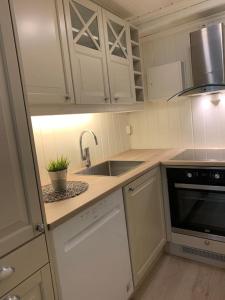 una cocina con armarios blancos y fregadero en Riverside apartment in Skien, en Skien