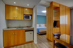 Habitación con cocina y dormitorio con cama. en Quality Suítes Oscar Freire, en São Paulo