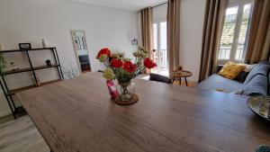 uma sala de estar com uma mesa de madeira com um vaso de flores em Un second souffle em Foix