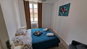 a small bedroom with a blue bed with a window at Un second souffle in Foix