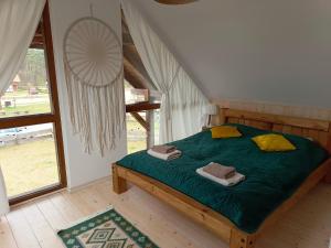 1 dormitorio con 1 cama con sábanas verdes y almohadas amarillas en Rozmaryn - Komfortowy domek całoroczny na Kaszubach, en Borowy Młyn