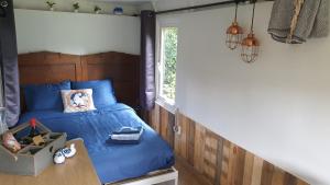 a bedroom with a blue bed and a window at Pipowagen Bed bij Bos in Putten