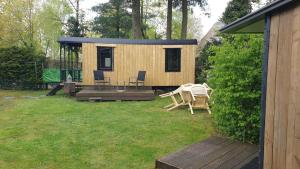 een tiny house in een yard met een terras bij Pipowagen Bed bij Bos in Putten