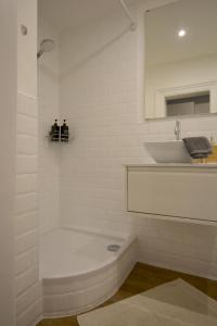 a white bathroom with a tub and a sink at MeetsLeopold in Vienna