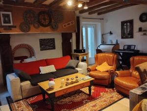sala de estar con sofá, mesa y piano en Longère de charme au calme de sa campagne environnante, en Marigné-Laillé