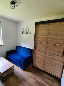 a living room with a blue couch next to a dresser at Noclegi przy Wiadukcie - Apartamenty in Lewin Kłodzki