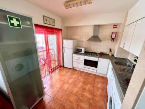 eine Küche mit weißen Geräten und einer roten Tür in der Unterkunft HSH Gomeira Cabanas Beach in Cabanas de Tavira