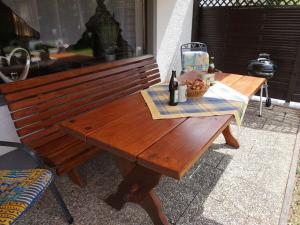 - un banc en bois avec une table et une bouteille de vin dans l'établissement Holiday apartment Brandl Haus 92, à Arrach