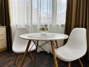 una mesa blanca con tres sillas blancas y una copa de vino. en ApartHotel Near the Sea, en Mamaia Nord – Năvodari