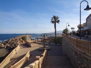 a walkway near the ocean with a table and a palm tree at La Sirena Baria15 in Villaricos