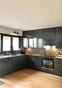 een grote keuken met zwarte kasten en houten vloeren bij Maison d'architecte 30 min Paris in Fontenay-aux-Roses
