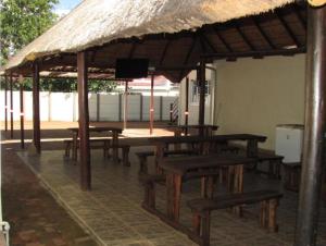 a group of wooden tables and benches under a pavilion at BelaBela Guesthouse in Bela-Bela