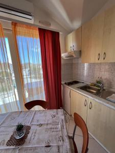 a kitchen with a table and chairs and a window at Apartmani Šaldi in Pakoštane