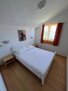 a bedroom with a white bed and a window at Apartmani Šaldi in Pakoštane
