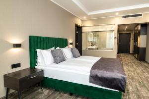 a bedroom with a large bed with a green headboard at Empire Balneo and Spa Hotel in Hisarya