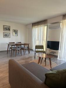 een woonkamer met een bank, tafels en een tv bij Appartement dans résidence avec piscine in Saint-Tropez