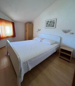 a bedroom with a large white bed in a room at Apartmani Šaldi in Pakoštane
