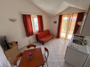 a kitchen and living room with a table and a red chair at Apartmani Šaldi in Pakoštane