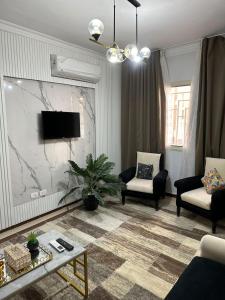 a living room with two chairs and a tv at Quite apartment with positive vibes in New cairo