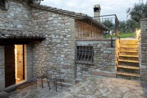 a stone house with two chairs on a patio at Casa Vacanze L'olivo al Borghettaccio in Assisi