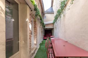un callejón con una mesa rosa y sillas en un edificio en La Maison des Chalands, en Blois