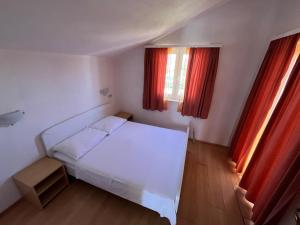 a bedroom with a white bed and two windows at Apartmani Šaldi in Pakoštane