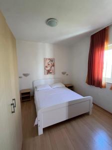 a bedroom with a white bed and a window at Apartmani Šaldi in Pakoštane