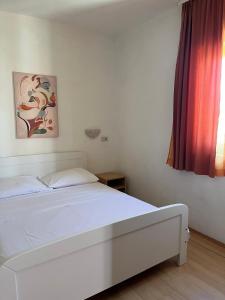 a white bed in a room with a window at Apartmani Šaldi in Pakoštane