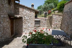a stone building with a patio with a table and flowers at Casa Vacanze L'olivo al Borghettaccio in Assisi