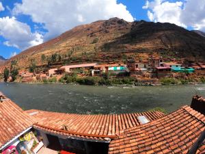 Aguaymanto hostel في بيساك: قريه على نهر مع جبل في الخلف