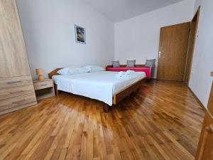 sypialnia z łóżkiem i drewnianą podłogą w obiekcie Apartments Rusin w Krku