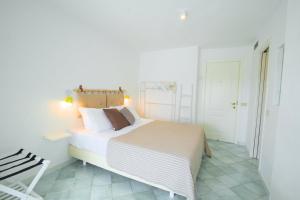 a white bedroom with a large bed and a chair at Villa Ravino Secret Retreat in Ischia
